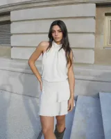 Vestido corto color beige, con cuello halter y espalda descubierta.