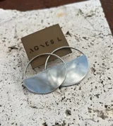 Aros colgantes plateados de diseño geométrico, con estructura circular superior y una placa inferior en forma de medio círculo texturizado.