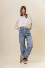 Pantalón de jean de corte recto y relajado, con tiro medio-alto. Presenta un estampado floral sutil en tonos claros sobre la base de denim azul y cuenta con interior forrado para mayor abrigo.
