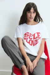 Remera blanca de algodón con estampa frontal en color rojo que forma un corazón con la frase 'Self Love'.