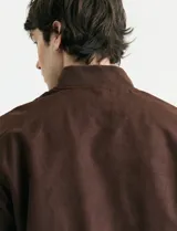 Campera tipo bomber de color marrón, confeccionada en tejido con textura similar a la gamuza, con cierre frontal completo, cuello redondo y puños elásticos.