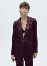 Chaqueta de corte recto con diseño de lentejuelas en color bordó, cuello con solapa, cierre frontal de un botón, manga larga y dos bolsillos delanteros con solapa.