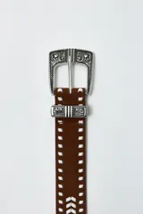 Cinturón de cuero color marrón con hebilla metálica plateada con diseño labrado y pespuntes en contraste.