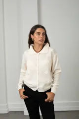 Saco de punto color blanco con cuello tipo polo, cierre frontal con botones y flores bordadas en relieve distribuidas por toda la prenda.
