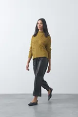 Polera de tejido de punto color marrón, con cuello alto y diseño de textura con relieves y trenzas. Posee mangas largas con puños acanalados.