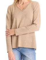 Buzo de tejido fino con acabado brillante de lurex, color beige, con escote en V, mangas largas con puños acanalados y ruedo con detalle de tejido acanalado más ancho.