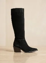 Bota de caña alta confeccionada en cuero vacuno negro con acabado mate. Presenta un diseño minimalista con taco cuadrado de 6 cm y suela de caucho antideslizante.