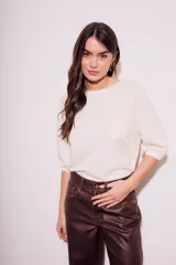 Remera de algodón color blanco roto, con escote redondo y mangas globo de tres cuartos con elástico en el puño.