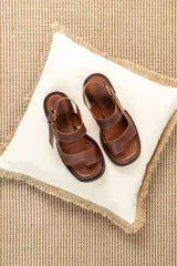 Sandalias de cuero marrón con diseño de punta abierta, tiras ajustables con hebilla metálica y suela de bloque bajo.