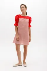 Vestido corto con rayas verticales rojas y blancas, cuello redondo y mangas cortas abullonadas rojas con elástico en el puño.