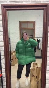 Campera puffer de corte oversize y diseño acolchado, color verde vibrante. Presenta cuello alto, cierre frontal con cremallera y botones a presión, y mangas largas con puños elásticos.