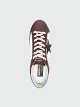 Zapatillas Golden Goose modelo Super Star, de cuero color marrón y blanco, con estrella negra en el lateral y detalles en celeste.