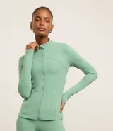 Campera deportiva de microfibra con cierre frontal, cuello alto y bolsillos laterales. Presenta recortes anatómicos que siguen la silueta, manga larga y diseño entallado.