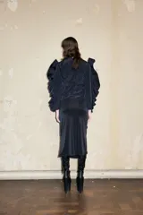 Falda midi negra de corte irregular con frente drapeado y detalle de herradura.