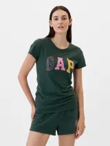 Remera de manga corta color verde oscuro con cuello redondo. Presenta el logo de la marca GAP estampado en el frente con letras de distintos colores: violeta, rosado y amarillo.