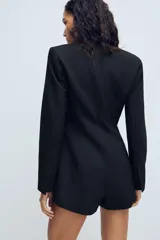 Mono tipo blazer de escote en pico y manga larga con hombreras. Presenta cierre frontal cruzado con botones, bolsillos de vivo en el delantero y forro interior a tono.