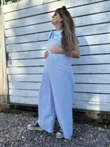 Mono largo de corte holgado con diseño de rayas verticales finas en azul y blanco. Presenta breteles anchos para atar sobre los hombros y piernas de corte ancho tipo palazzo.