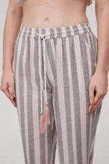 Pantalón babucha celeste con rayas verticales blancas, cintura elástica con cordón y detalle de borlas.