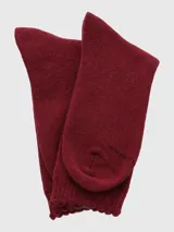 Calcetín de largo medio en tejido grueso color bordó, con puño suave y detalle de etiqueta con logo en la parte superior.