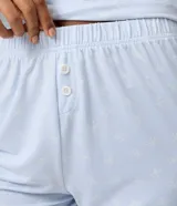 Short de pijama celeste de peach touch con estampa de moñitas blancas, cintura elastizada con bragueta frontal de botones y detalle de encaje blanco en los bajos.
