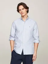 Camisa de corte regular confeccionada en algodón Oxford, con diseño de rayas verticales en tonos blanco y azul. Presenta cuello con botones, puños redondeados y logo de la marca bordado en el pecho.