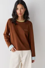 Remera de manga larga color marrón con cuello redondo en tono verde claro y puños en tono celeste. Presenta el logo de la marca bordado en el pecho.