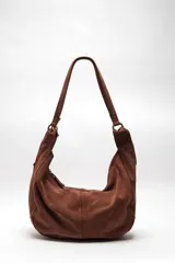 Bolso tote de ante suave, de cuerpo blando estilo hobo, con asa larga para el hombro y cierre superior con cremallera.