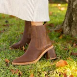 Botas tipo chelsea de cuero vacuno color marrón, con elásticos laterales, punta fina y taco cuadrado forrado en cuero.