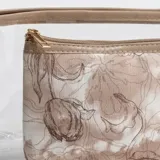 Pack de dos necessaires, uno transparente y otro con estampa floral en tonos beige, ambos con cierre superior y detalles en color beige.