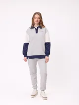 Sweater estilo rugby de Rusty, con diseño color block en tonos bordó, azul marino y verde. Presenta cuello polo en color crema con cierre frontal de botones, mangas largas con puños elásticos y logo de la marca bordado en el pecho.