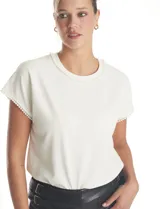 Blusa de crepe color blanco, con cuello redondo y mangas cortas. Presenta apliques de perlas decorativas en el borde del cuello y en los extremos de las mangas.
