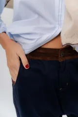 Pantalón de gabardina azul marino, de corte barrel y tiro bajo, con detalles en pana marrón en la pretina y en el ruedo interior vuelto.