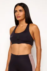 Top deportivo negro con cierre frontal, espalda cruzada y logo estampado en el pecho. Cuenta con abertura interna para copas removibles.