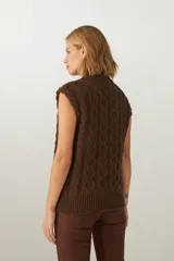 Chaleco de punto color crema con diseño trenzado y cuello en V.