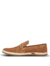 Mocasín Hush Puppies modelo Montella, confeccionado en descarne color tostado. Presenta un diseño clásico con detalle de antifaz y suela con borde de yute trenzado, combinando elegancia y estilo natural.