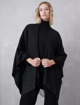 Ruana negra de tejido soft, con detalles de brillos y perlas en los extremos, y terminación con flecos.