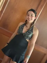 Vestido corto negro con estampado de plumas doradas, escote en V, breteles finos cruzados en la espalda, cut-outs laterales y volado en el ruedo.