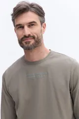 Remera de manga larga Brooksfield color marrón, con cuello redondo y textura sutil. Presenta un estampado frontal con el logo y leyenda de la marca.