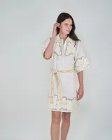 Vestido corto de lino blanco con cuello clásico, mangas cortas y detalles bordados florales tono sobre tono con inserciones translúcidas. Incluye un cinturón de tela ajustable con estampado.