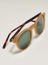 Anteojos de sol con armazón negro mate y forma redonda. Lentes con filtro degradado oscuro.