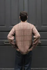 Buzo tejido de punto con diseño geométrico de cuadrillé en tonos azul y verde. Presenta cuello redondo, mangas largas y un parche de cuero sintético con logo en el pecho.