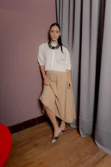 Falda midi de corte amplio y caída suave, color beige, con cintura elástica y bolsillos laterales.