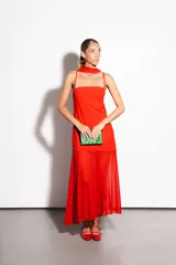 Vestido largo negro confeccionado en crepé y gasa, de corte al cuerpo con escote recto, tiritas finas y falda larga semitransparente con tajo lateral pronunciado. Incluye accesorio tipo corbatín a juego.