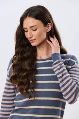 Buzo tejido de algodón con diseño a rayas horizontales, cuello redondo y mangas largas. El cuerpo presenta rayas en tonos azul y beige, mientras que las mangas combinan rayas en tonos azul y rosado.