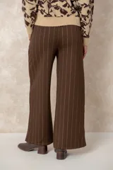 Pantalón de corte ancho y tiro alto, confeccionado en tejido azul marino con finas rayas verticales de hilo de lurex plateado. Presenta cintura con pasacintos y se incluye un cinturón negro con hebilla metálica.