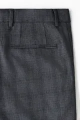 Pantalón de traje gris con sutil patrón a cuadros, corte slim fit con raya marcada en las piernas, bolsillos laterales y bolsillos traseros ribeteados.