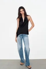 Top de satén con cuello halter, diseño drapeado en el frente y bajo asimétrico. Presenta espalda descubierta y cierre con lazada en el cuello.