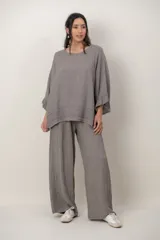 Blusa de lino color verde militar, holgada, de manga 3/4 con volados en los puños, cuello redondo y detalle de alforzas horizontales en el dobladillo.