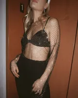 Top de red negro con strass, mangas largas y cuello redondo. Incluye corpiño negro con breteles finos.