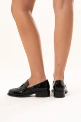 Mocasín de cuero charol negro con diseño enrejillado en la capellada, horma cuadrada y taco bajo.
